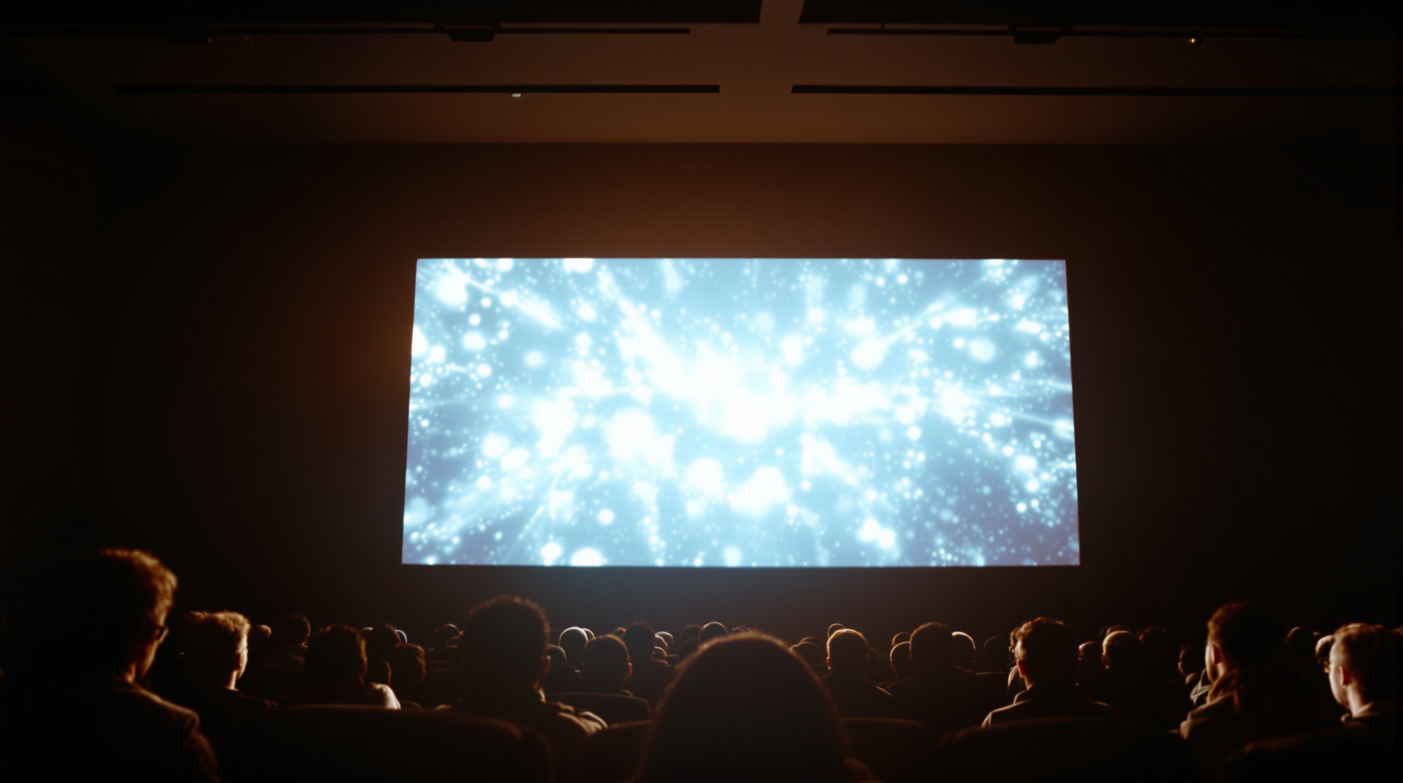 Silhouettes of an audience watching a bright cinema screen together
